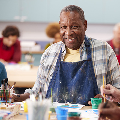 elderly man smiling while painting with other residents