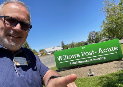 The Administrator, Don Wessels, pointing to the Willows Post Acute monument sign
